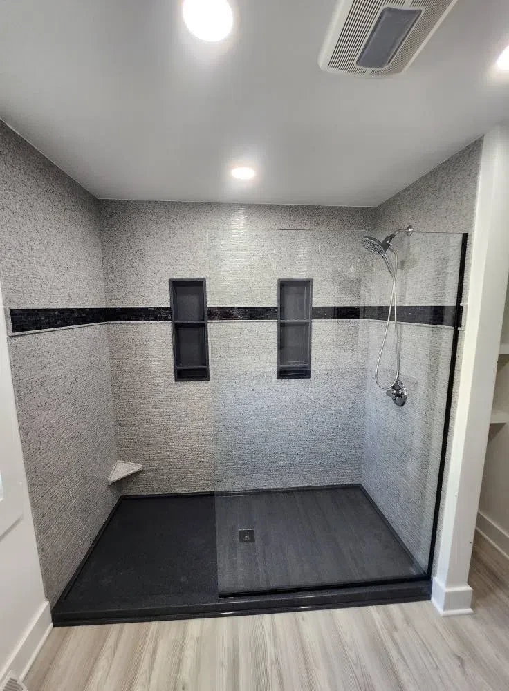 Custom walk-in shower with black base and tile niches